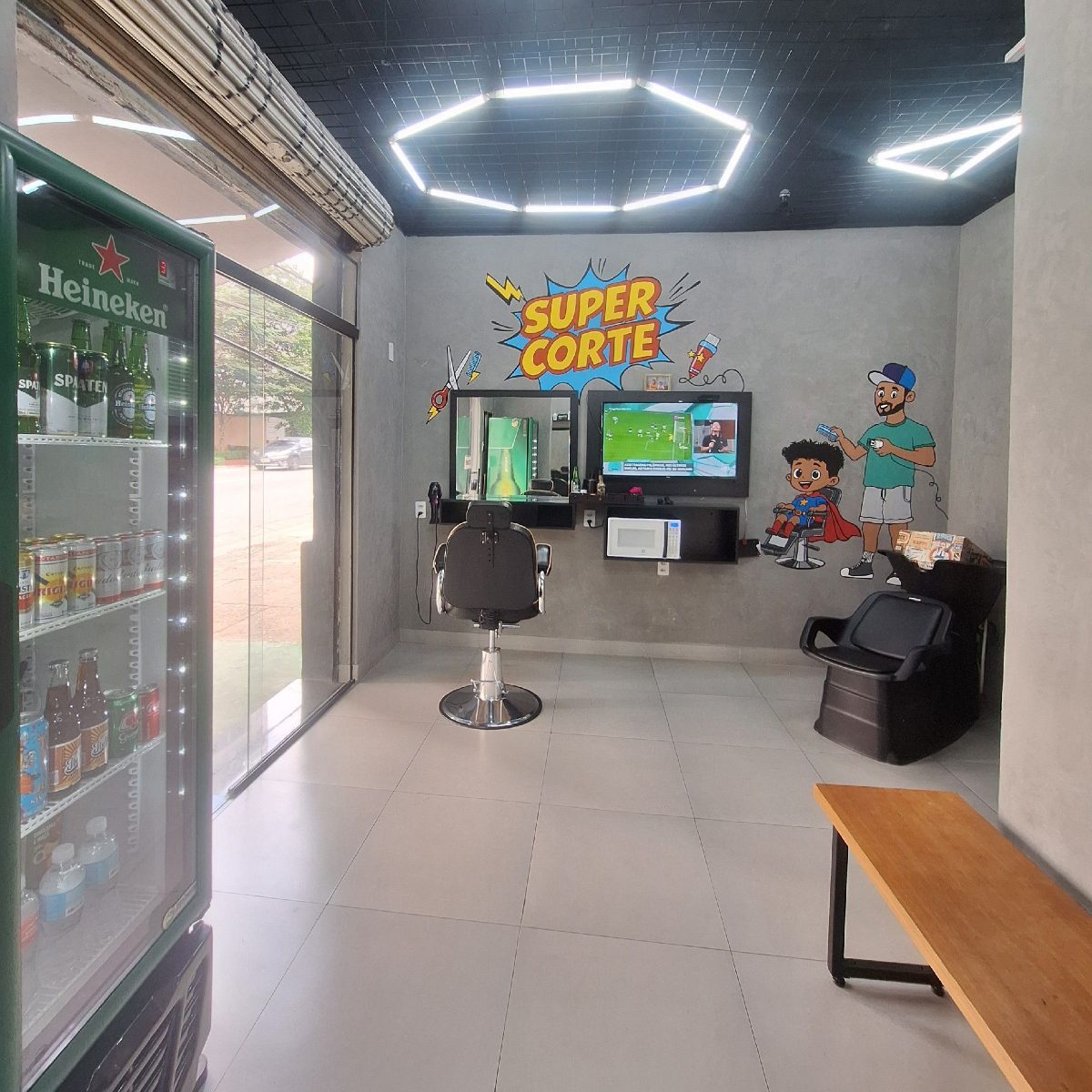 Espaço da New Style com geladeira de bebidas, lavatório e teto de luzes geométricas